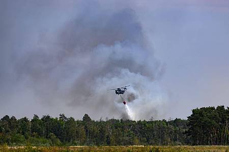 Robert Michael/dpa | Ein Löschhubschrauber ist beim Waldbrand in der Gohrischheide im Einsatz.