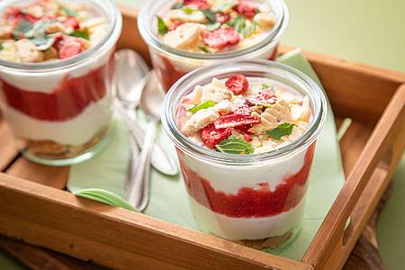 Christin Klose/dpa-tmn | Das Schichtdessert im Glas besteht aus Mascapone-Joghurt-Creme, Keksbröseln, Erdbeerpüree, getrockneten Erdbeeren, weißen Schokoraspeln und Minze.