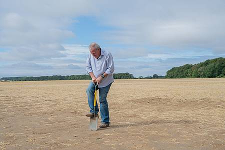 Jeremy Clarkson sticht mit einem Spaten in getrockneten Acker.