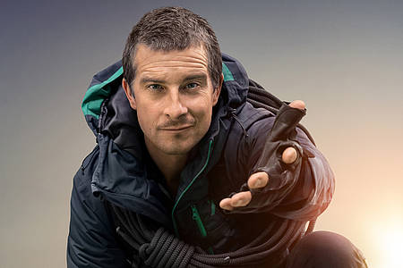 Bear Grylls streckt die Hand zur Kamera aus