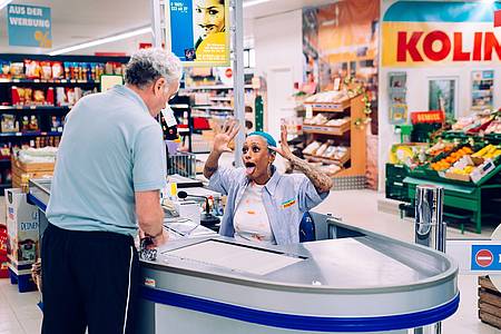 Discounter-Mitarbeiterin an der Kasse streckt die Zunge raus und zieht eine Grimasse