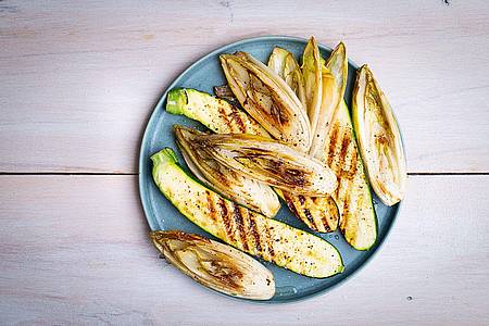 Ariane Bille/BVEO/dpa-tmn | Die länglich geschnittenen Zucchini- und Chicorée-Streifen werden mit einer Marinade aus Olivenöl, Limettensaft, Salz und Pfeffer eingepinselt, dann auf jeder Seite 2?3 Minuten gegrillt.