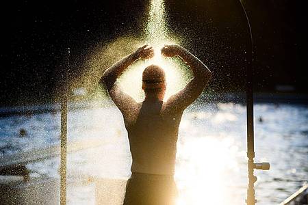 Julian Stratenschulte/dpa/dpa-tmn | Ist der Körper aufgeheizt, sollte man sich vor dem Baden einmal kurz abbrausen oder etwas Wasser über Arme, Beine und Rumpf spritzen.