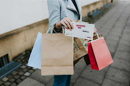 frau hält viele taschen in der hand und einen gutschein