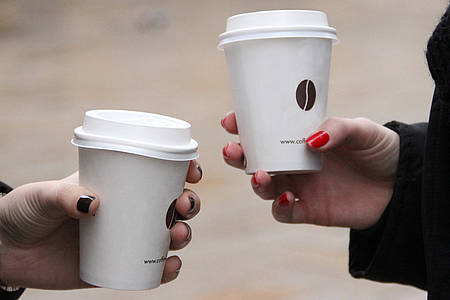 Zwei Hände halten jeweils einen Kaffee-to-go Becher