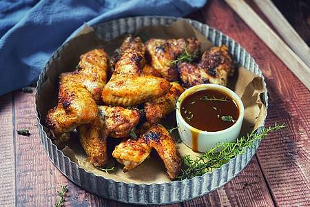 Anja Würfl/die-frau-am-grill.de/dpa-tmn | Damit nichts in die Glut tropft, empfiehlt sich für die Chicken Wings eine sämige Marinade aus Trockengewürzen.