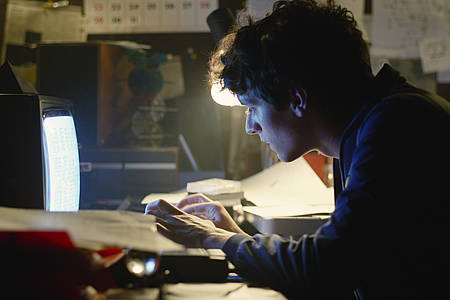 Junger Mann aus dem Film Black Mirror: Bandersnatch schaut auf einen Bildschirm und tippt