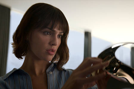 Eiza González als Auggie Salazar begutachtet eine Virtual Reality Brille