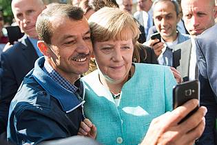 Bernd von Jutrczenka/dpa | Bald zehn Jahre her: Angela Merkel (CDU) lässt sich nach dem Besuch einer Erstaufnahmeeinrichtung für Asylbewerber in Berlin-Spandau für ein Selfie zusammen mit einem Flüchtling fotografieren. (Archivbild)