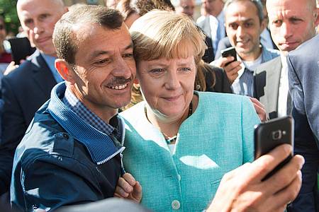 Bernd von Jutrczenka/dpa | Bald zehn Jahre her: Angela Merkel (CDU) lässt sich nach dem Besuch einer Erstaufnahmeeinrichtung für Asylbewerber in Berlin-Spandau für ein Selfie zusammen mit einem Flüchtling fotografieren. (Archivbild)