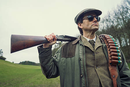 David Tennant als Tony Baddinham schultert ein Gewehr im Jagdoutfit - Rivals auf Disney+.