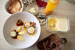 Christin Klose/dpa-tmn | Mangoeis und Schokoladenmousse werden auf Mango- und Erdbeerpüree-Klecksen angerichtet. Splitter von weißer Schokolade und frischen Himbeeren toppen die Kreation. 