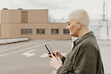 Frau mit Smartphone und Airpods-Kopfhörern