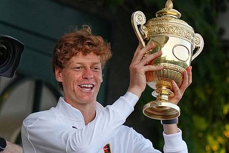 Joanna Chan/AP/dpa | Jannik Sinner präsentiert die Trophäe für den Wimbledonsieg.