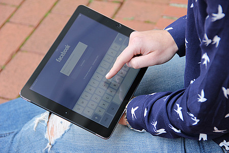 Hand die auf Tablet in der Facebook App tippt