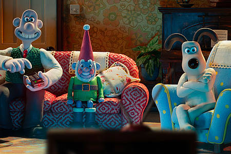 Die Knetfiguren Wallace und Gromit sitzen samt Gartenzwerg auf dem Sofa und schauen Fernsehen.