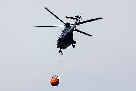 Daniel Wagner/dpa | Ein Löschhubschrauber der Bundespolizei fliegt über dem Zeithainer Tagebau und nimmt Wasser auf, um den Waldbrand Gohrischheide zu bekämpfen.