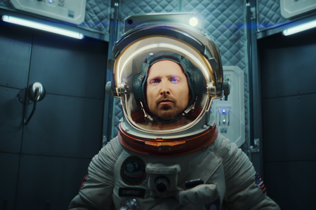 Aaron Paul in seiner Rolle als Astronaut bei Black Mirror trägt in einer engen Kapsel einen Raumanzug. 