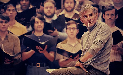 Bradley Cooper als Leonard Bernstein in Maestro sitzt vor einem erwartungsvollen Chor.