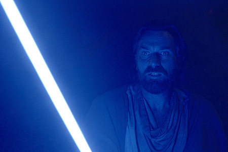 Obi-Wan Kenobi steht in der Dunkelheit, sein Gesicht von seinem Lichtschwert erleuchtet