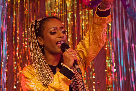 Rapperin Nura performt in der Rolle von Kassiererin Flora