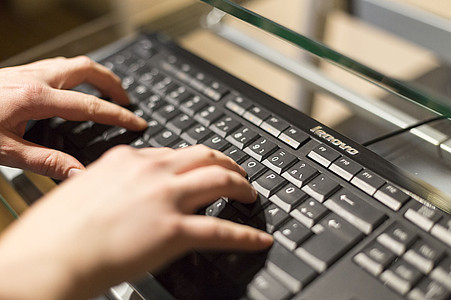 Finger tippen auf schwarzer Tastatur.