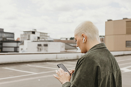 Frau mit Smartphone und Airpods-Kopfhörern