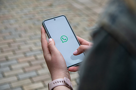 Hand hält ein Smartphone mit WhatsApp Startbildschirm