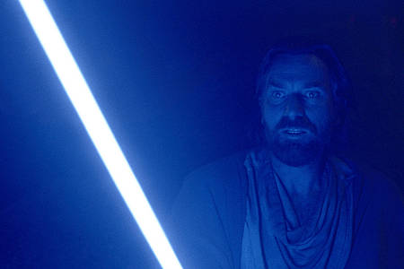 Obi-Wan Kenobi steht in der Dunkelheit, sein Gesicht von seinem Lichtschwert erleuchtet